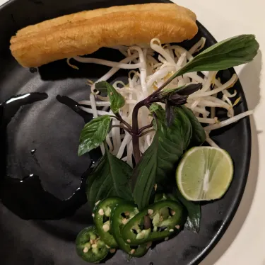 A plate of herbs used to top beef noodle soup